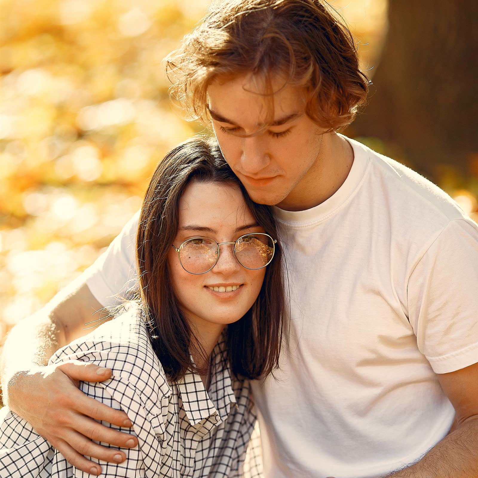 A couple sitting close together in an autumn park