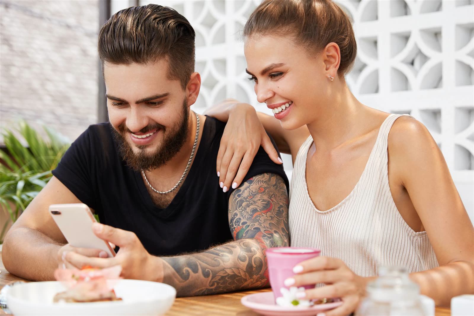 Two people laughing together over coffee at a café table